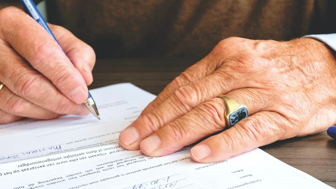 An elderly person signing documents