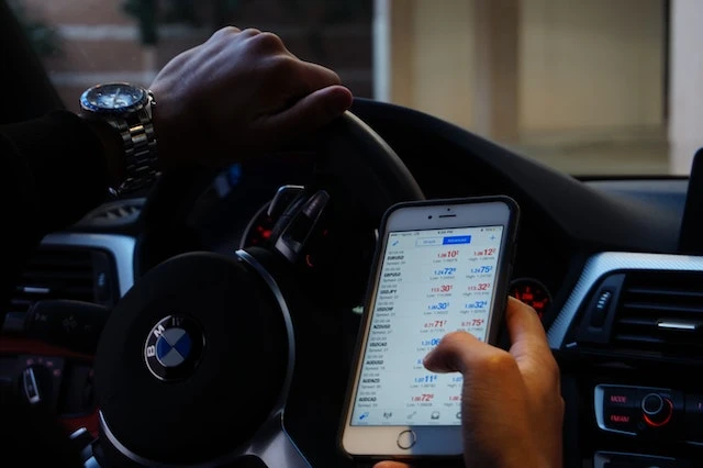 Man driving a car and using a phone to check their crypto wallet