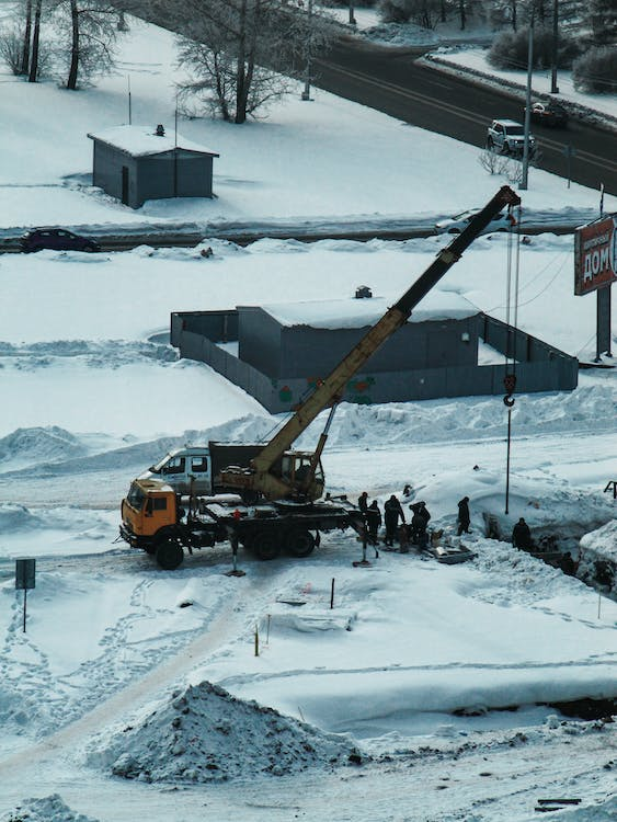 A crane is being used on a site with fallen snow.