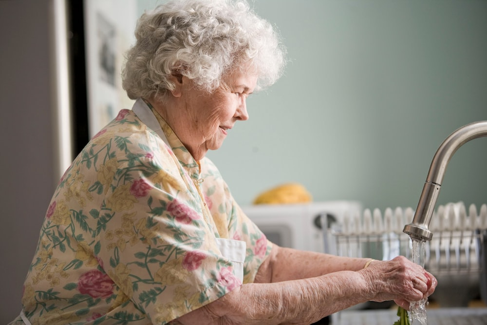 an elderly woman doing the dishes