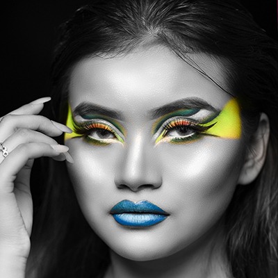  A woman is wearing eye-catching makeup, with her eye standing out in yellow and blue colors.